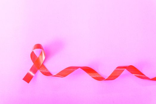 Red Ribbon Support HIV, AIDS on pink background and copy space for use