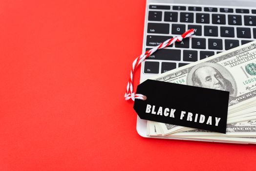 Online shopping, Promotion Black Friday Sale text on black tag with computer laptop and money on red background.