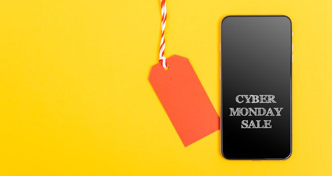 Internet Online shopping,  Blank red tag and Smartphone have message Cyber Monday sale in screen on yellow background and have copy space for use