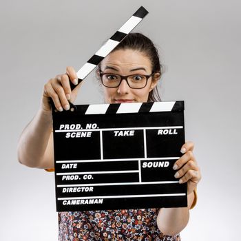 Portrait of a happy woman holding a clapboard