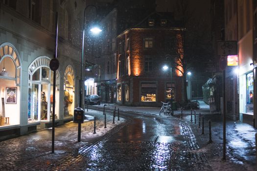 Snowy empty street at night in Aachen, Germany - lights and reflections