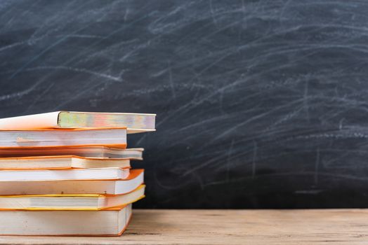 Classroom, with stack books on table have blackboard and chalkboard on background, back to school concept