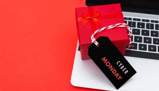 Online shopping, Promotion Cyber Monday Sale text on black tag with computer laptop and gift box on red background