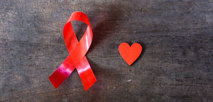 Red Ribbon Support HIV, AIDS and red Heart on wooden background and copy space for use