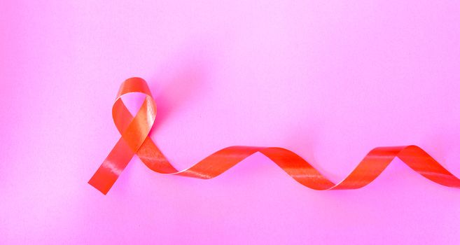 Red Ribbon Support HIV, AIDS on pink background and copy space for use