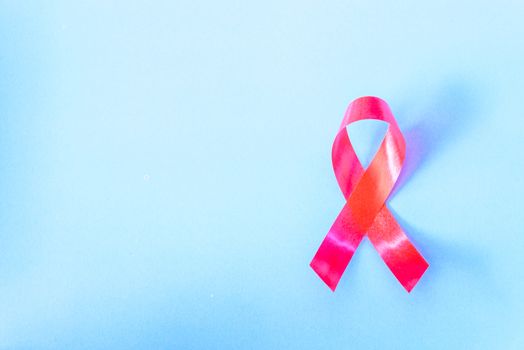 Red Ribbon Support HIV, AIDS on blue background and copy space for use