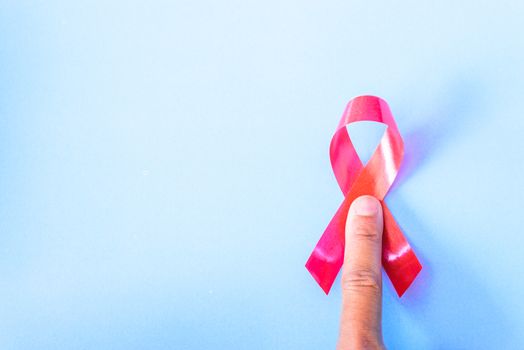 Red Ribbon Support HIV, AIDS and have finger point on blue background and copy space for use