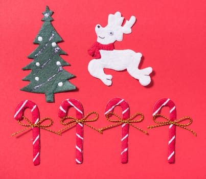 Christmas candies candy cane, deer, and tree on red background