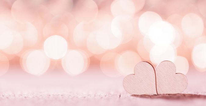Two handmade wooden pink hearts on beautiful bokeh background. Vintage style. Love Valentine's Day concept.