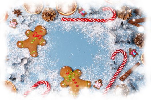Christmas food frame. Gingerbread cookies, spices and decorations on blue background with copy space