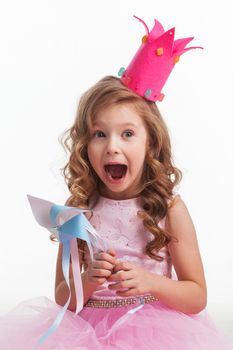 Beautiful little candy princess girl in crown holding pinwheel and screaming in joy