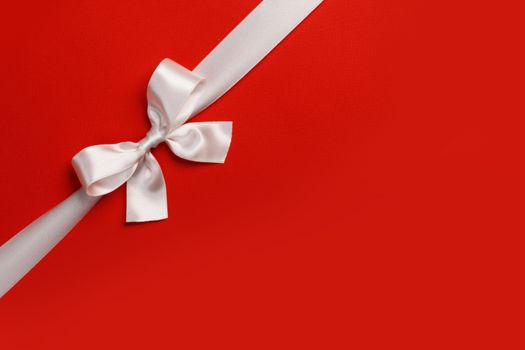 White gift bow on red background copy space for text holiday gift concept