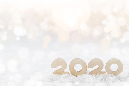 Wooden Number 2020 in the snow , Happy New Year's concept on glitter bokeh background