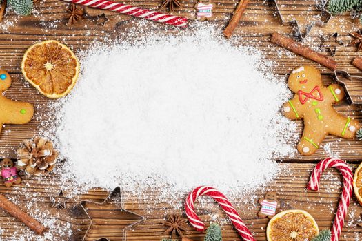 Christmas food frame. Gingerbread cookies, spices and decorations on wooden background with copy space on snow