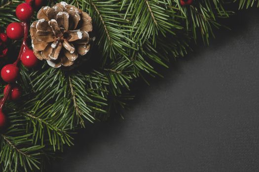 Pine Christmas tree branches cone and red berries on black paper background flat lay top view mock-up