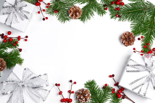 Christmas tree branch with snow , pine cones, red berries and gift boxes on white background with copy space