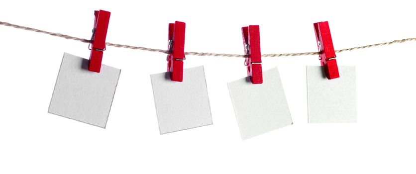 Set of four blank paper notes held on a string with clothespins isolated on white background