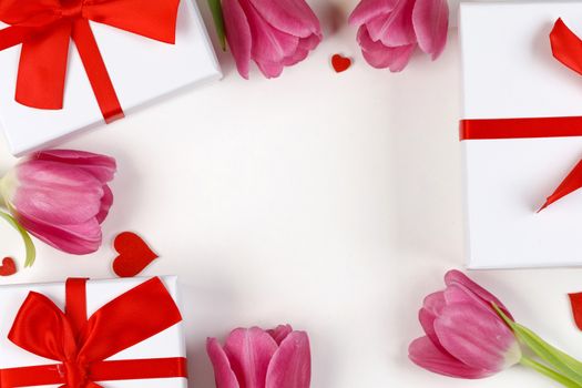 Pink tulips gifts and hearts border frame with copy space on white background Valentines day concept