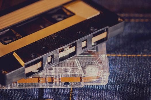 Cassette tape audio on jeans fabric in darkness. Concept of vintage 90s music player.
