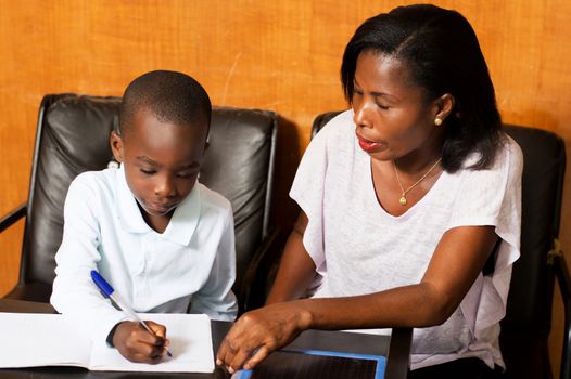 Mom attends child writing in his notebook.