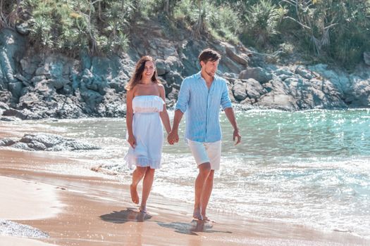 Happy couple walking on sand of tropical beach