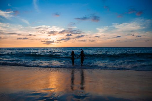 Happy female friends having fun on beach at sunset