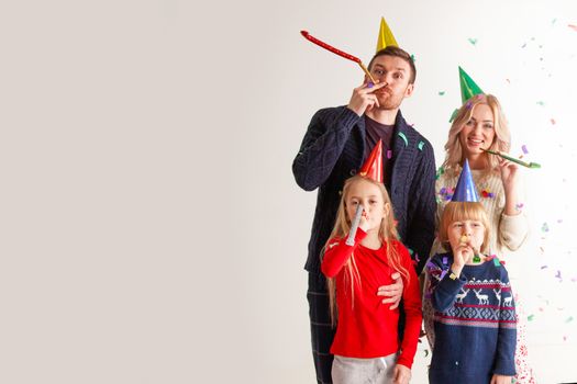 Family blowing party trumpets with confetti celebrating new year