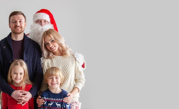 Portrait of young family with two children with Santa Claus, gray background with copy space for text