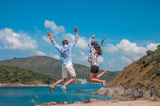 Young couple jumping, beautiful sea view on background