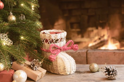 Gifts and wisker stocking under the Christmas tree in the room with a fireplace on Christmas eve.