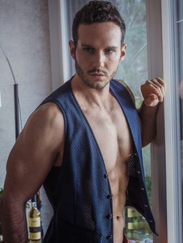 Handsome shirtless muscular man at home standing and looking away