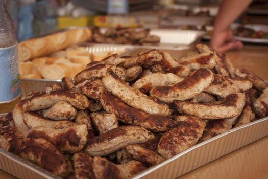 Tray full of pork sausages at a grill