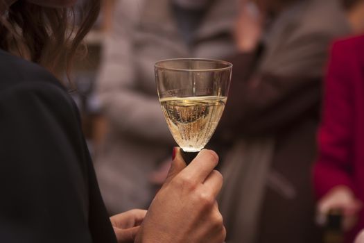 girl holding in her hand a glass of sparkling white wine at a party.