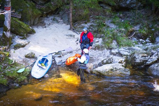 Man and woman on the kayak. A view of the sport is kayaking.A man and a woman on the bank of the river are resting pouring water from boats, carrying kayak to river.