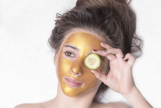 Beautiful girl with a cosmetic mask on the face of golden color. Beautiful model removing golden facial skin cosmetic. Beauty skincare .Close-up. Free space. Woman gold mask. .