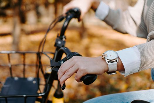 Riding a bike on a sunny day in autumn park. Female hand on a bicycle wheel