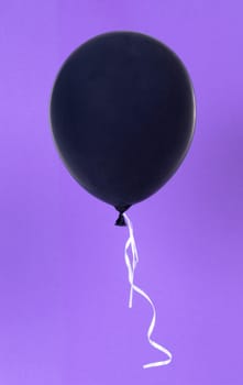 Black balloon isolated on a purple background