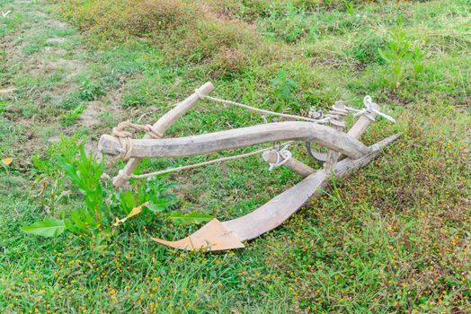 Close-up an ancient plow near fallow rice field at Lao Cai, North Vietnam. It is attached to a buffalo or a bull to turn soil. Traditional and manual agricultural tool concept.