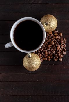 Cup of coffee with coffee beans and two Christmas balls on wooden background.Christmas and new year concept.Copyspace down.