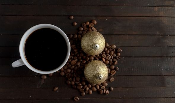 Cup of coffee with coffee beans and two pair Christmas golden balls on wooden background.Christmas and new year concept.Copyspace.
