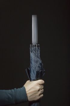 Female hand with folded umbrella on a black background