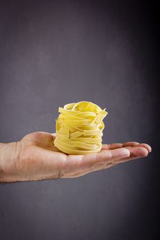 Italian pasta on a male hand on a black background