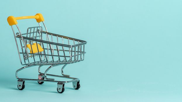 Shopping cart on blue background. Shop trolley at supermarket as sale, discount, shopaholism concept with copy space for text or design.