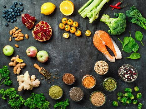 Clean Eating concept with copy space in center. Selection food ingredients for Clean Eating on dark background. Top view or flat lay.