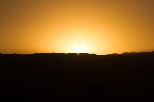 black silhouette of the mountains at sunset with golden sky