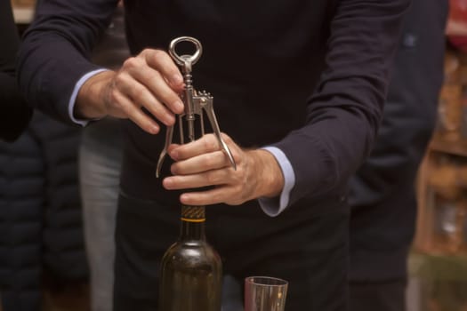 Open a bottle of wine with a corkscrew at a party.