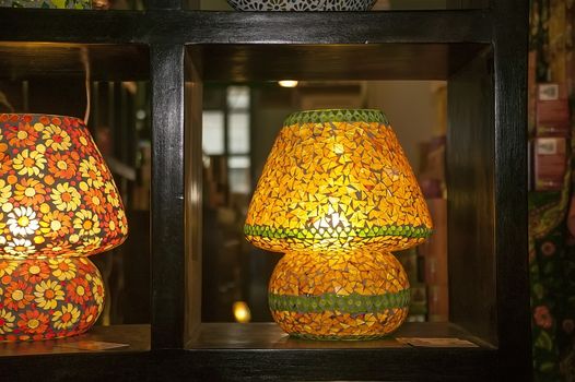 Lamp made of yellow glass pieces for a hot lizard, leaning on a dark wooden bookcase: tastefully decorated.