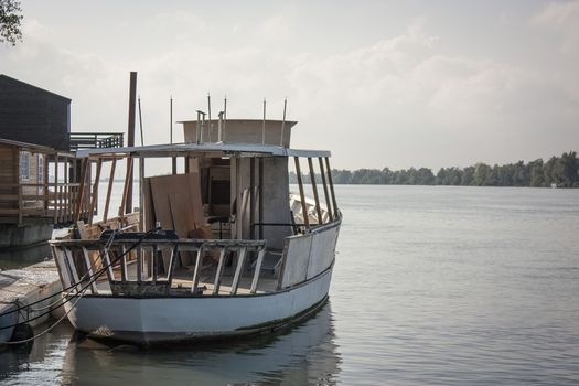 Small abandoned boat stationary and moored on the banks of the river po in italy.