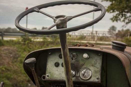 Steering wheel and instrument panel (or dashboard) of a vintage tractor used as a working tool to cultivate fields.