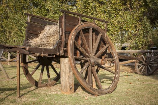 Old and worn vintage wooden carriage used as a decor element inside a countryside garden.